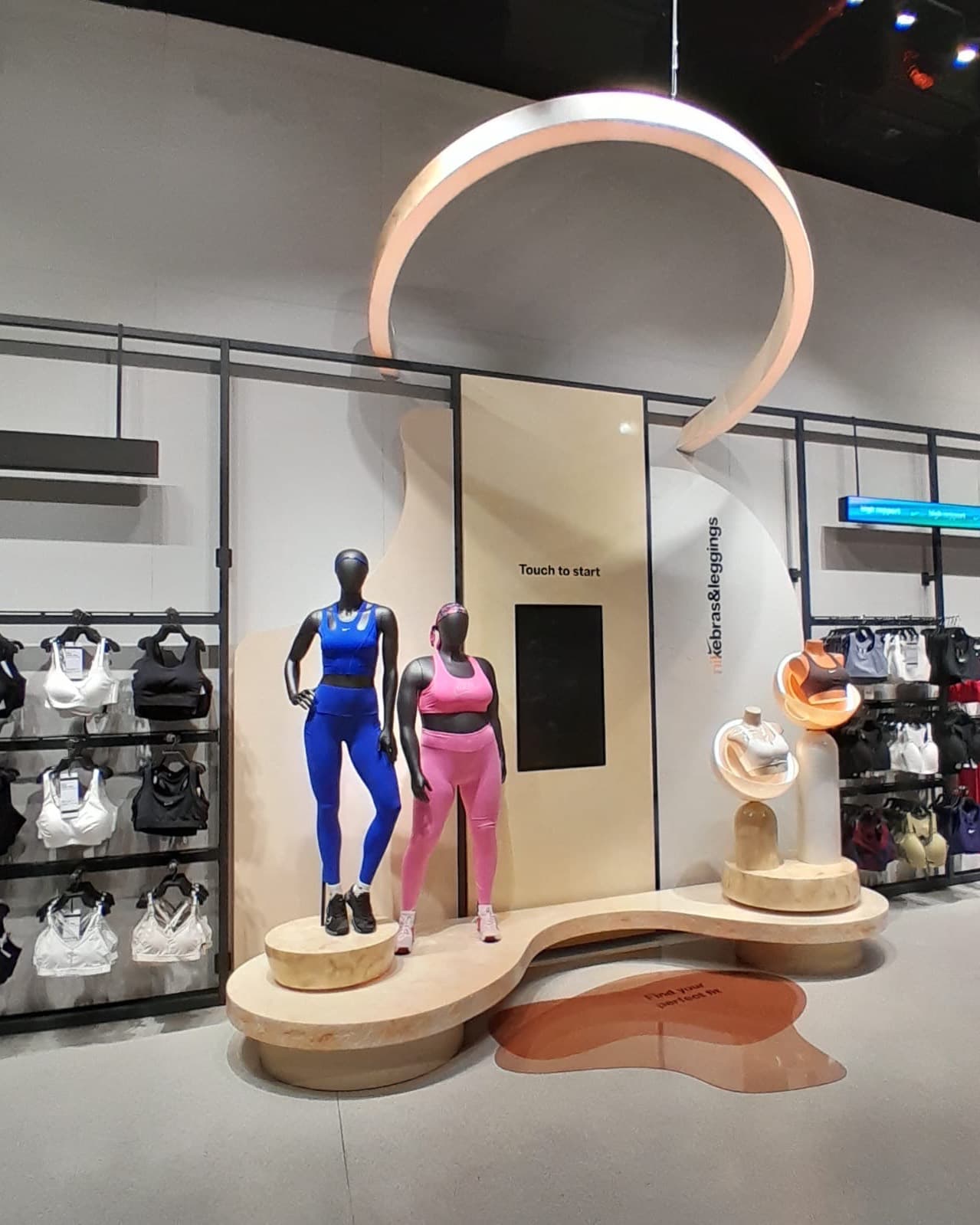 Custom retail display structure with a curved timber podium, suspended arch and product plinths